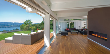 Wohnzimmerbereich mit hochwertigen Parkett und Terrasse mit Holzdielen.