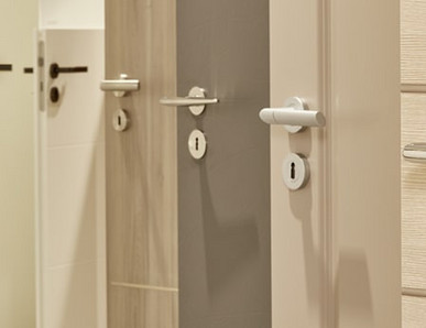 Mehrere nebeneinander angeordnete Türblätter in unterschiedlichen Farbtönen (weiß, holzähnlich, grau) mit integrierten Türgriffen.