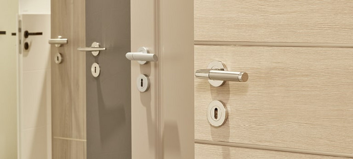 Mehrere nebeneinander angeordnete Türblätter in unterschiedlichen Farbtönen (weiß, holzähnlich, grau) mit integrierten Türgriffen.